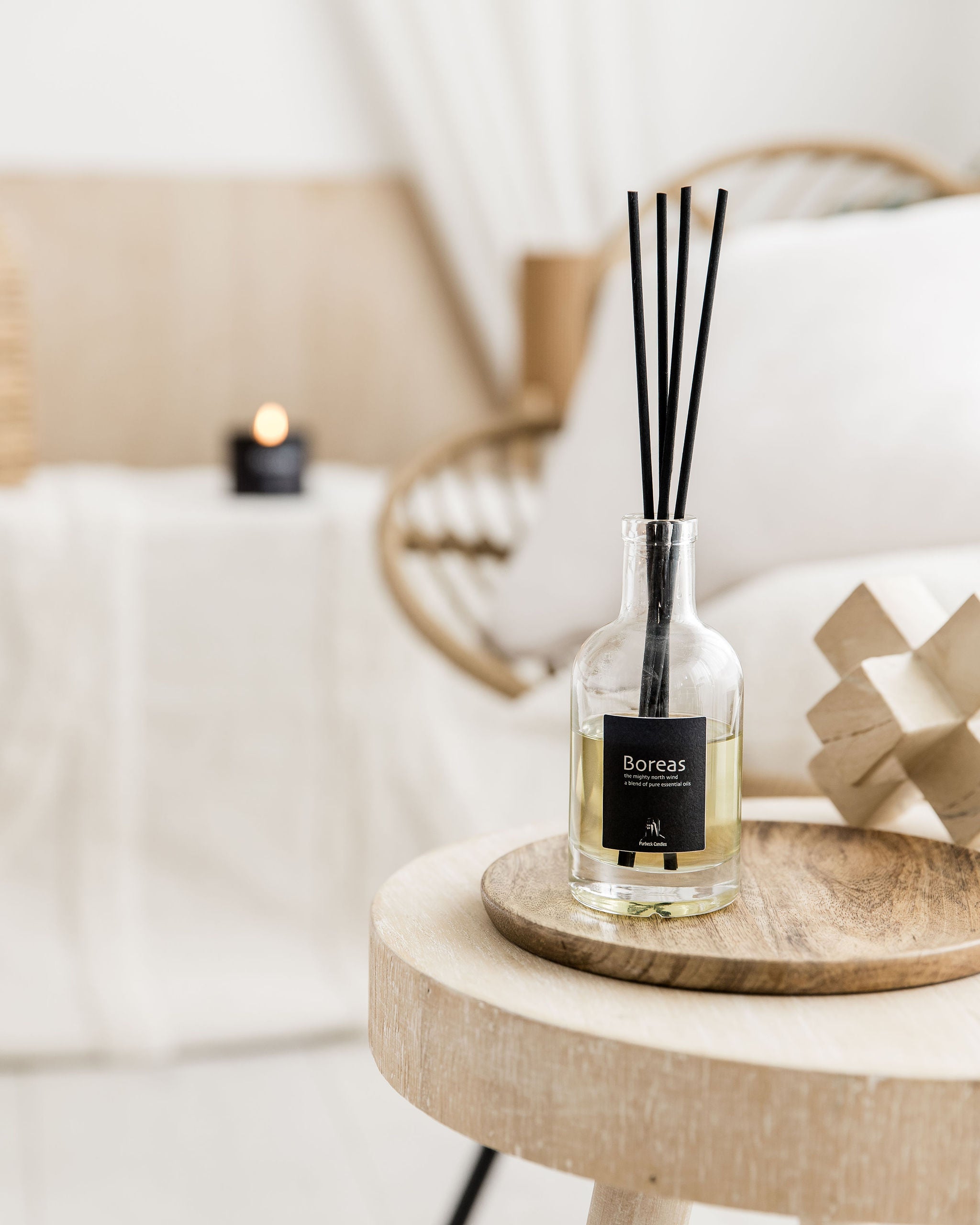 Boreas diffuser bottle with black sticks on a wooden table in a cozy room setting.