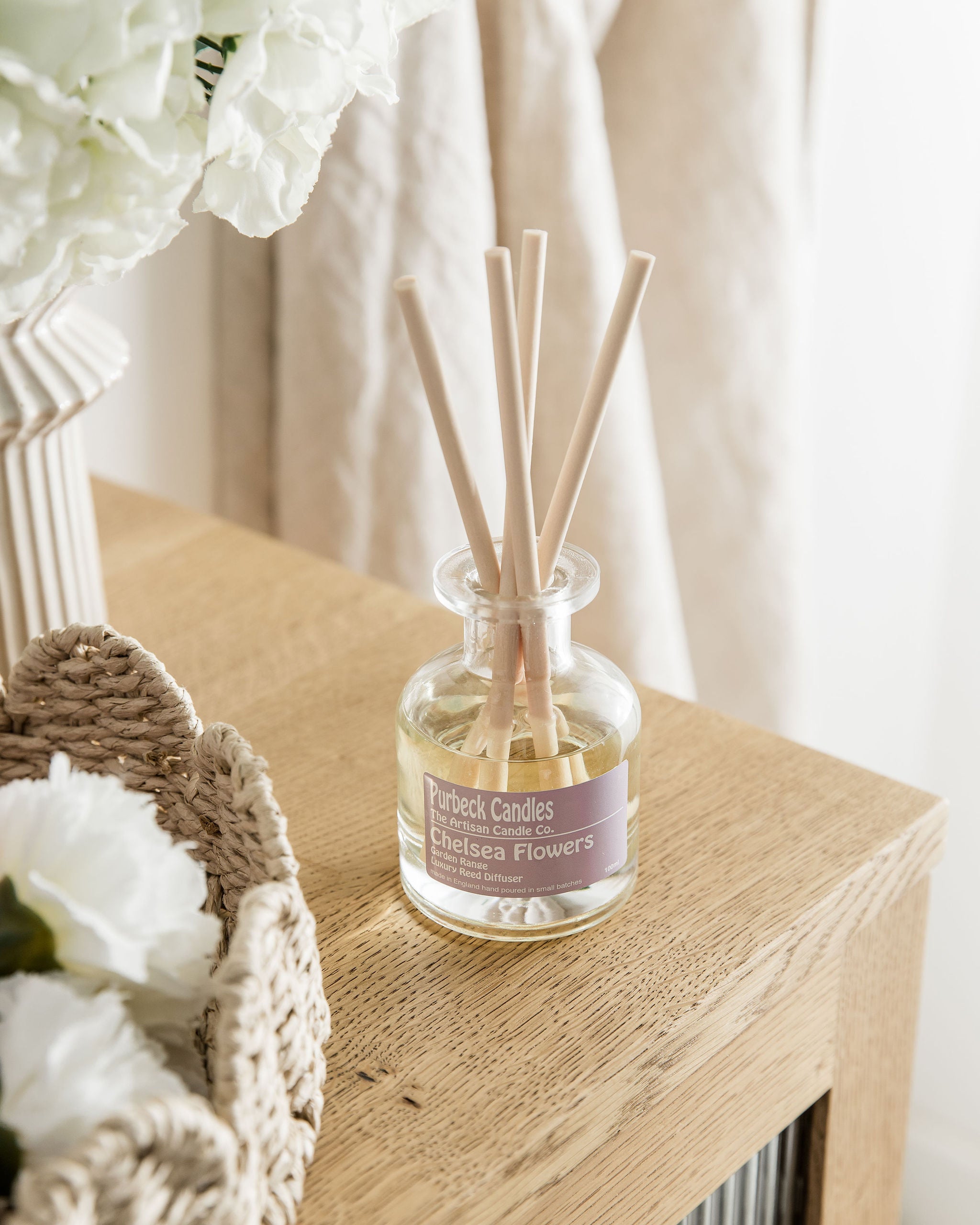 Diffuser with reeds and a decorative bottle on a wooden surface