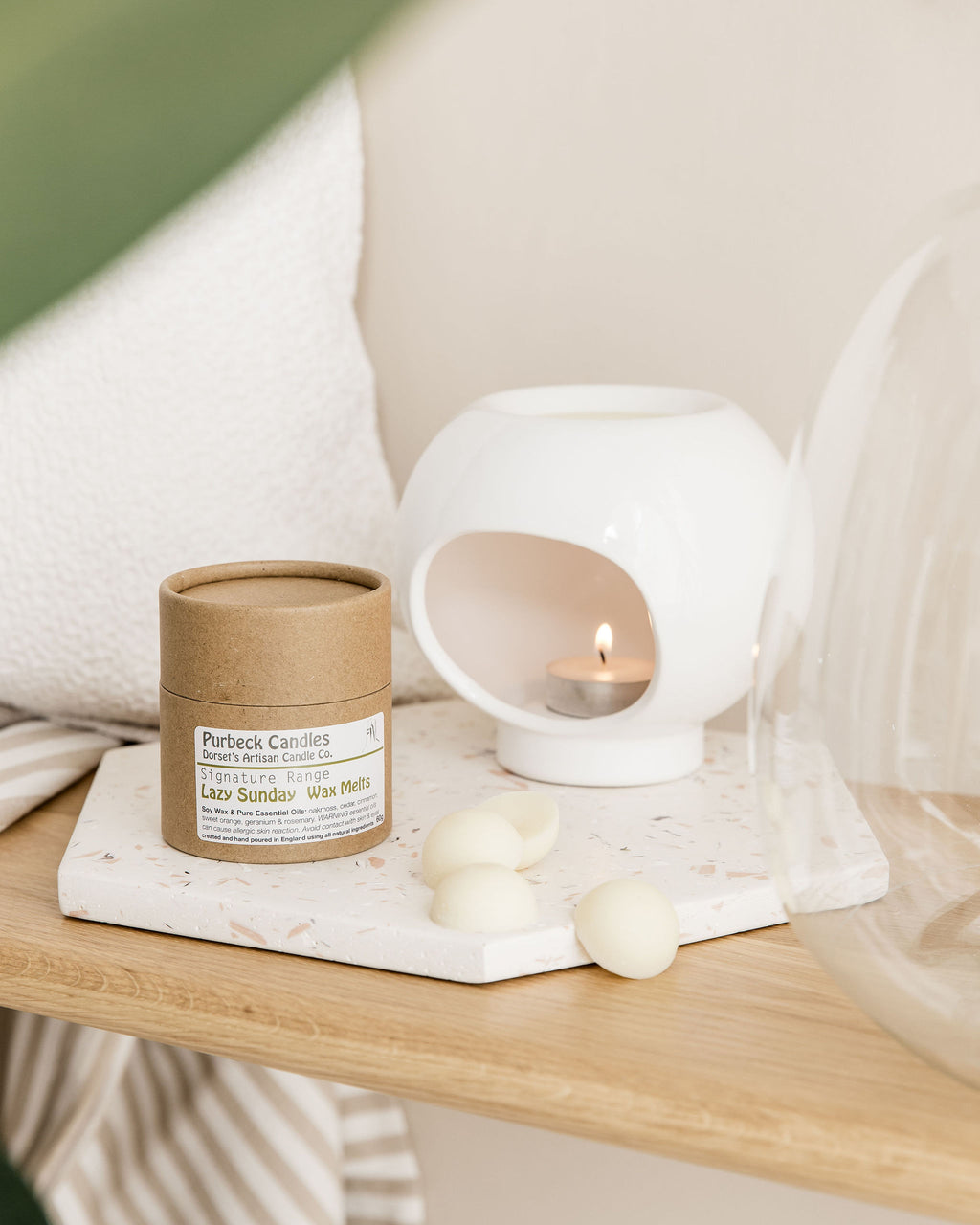 Wax Melts in a brown cardboard sleeve with a white candle holder on a wooden surface.