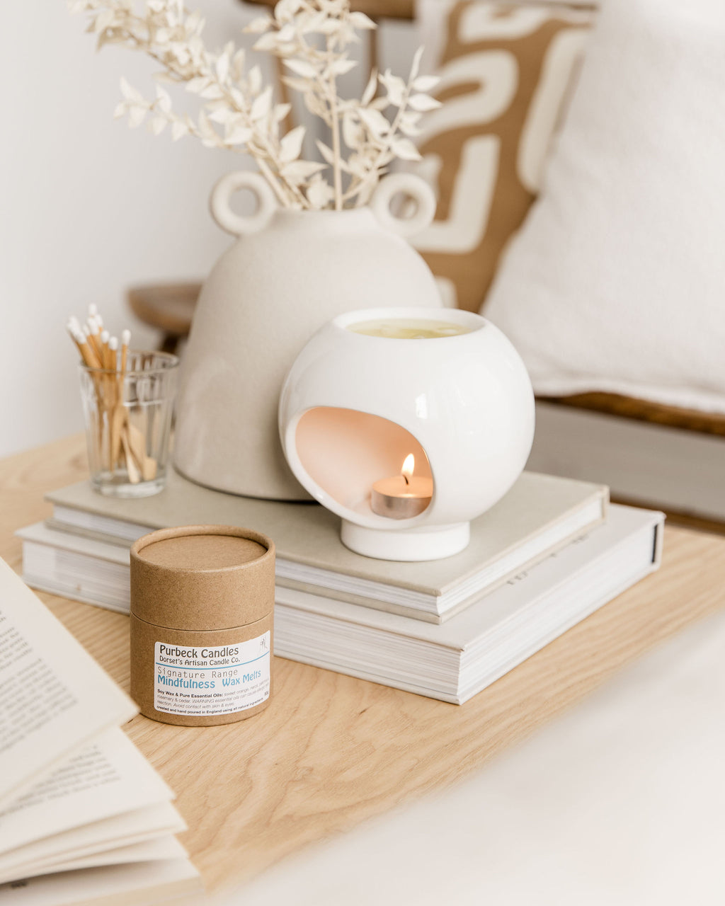 Candle and books on a wooden surface with a neutral color palette