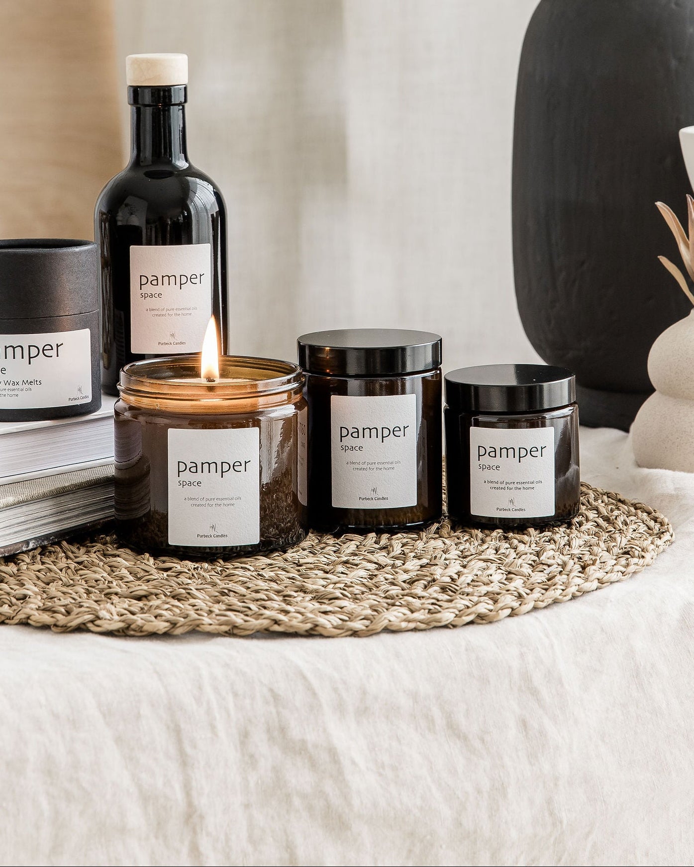 Collection of 'pamper' branded products including candles and bottles on a textured surface.