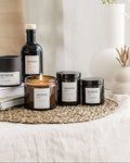 Collection of 'serene' branded candles and bottles on a textured surface with a neutral background.