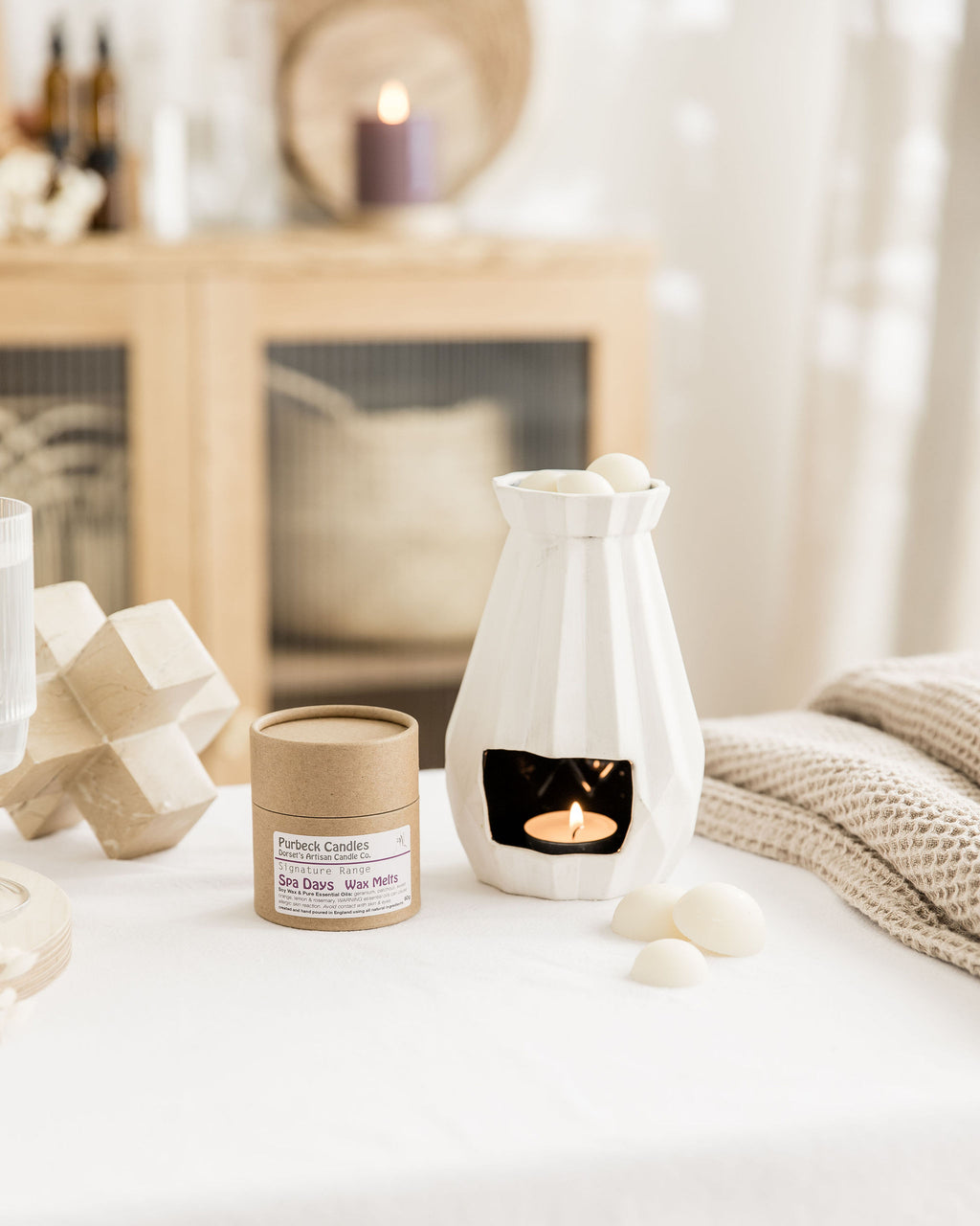 Wax melt container and melter on a table with a cozy indoor setting