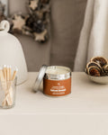 Candle in a decorative setting with matches and pinecones