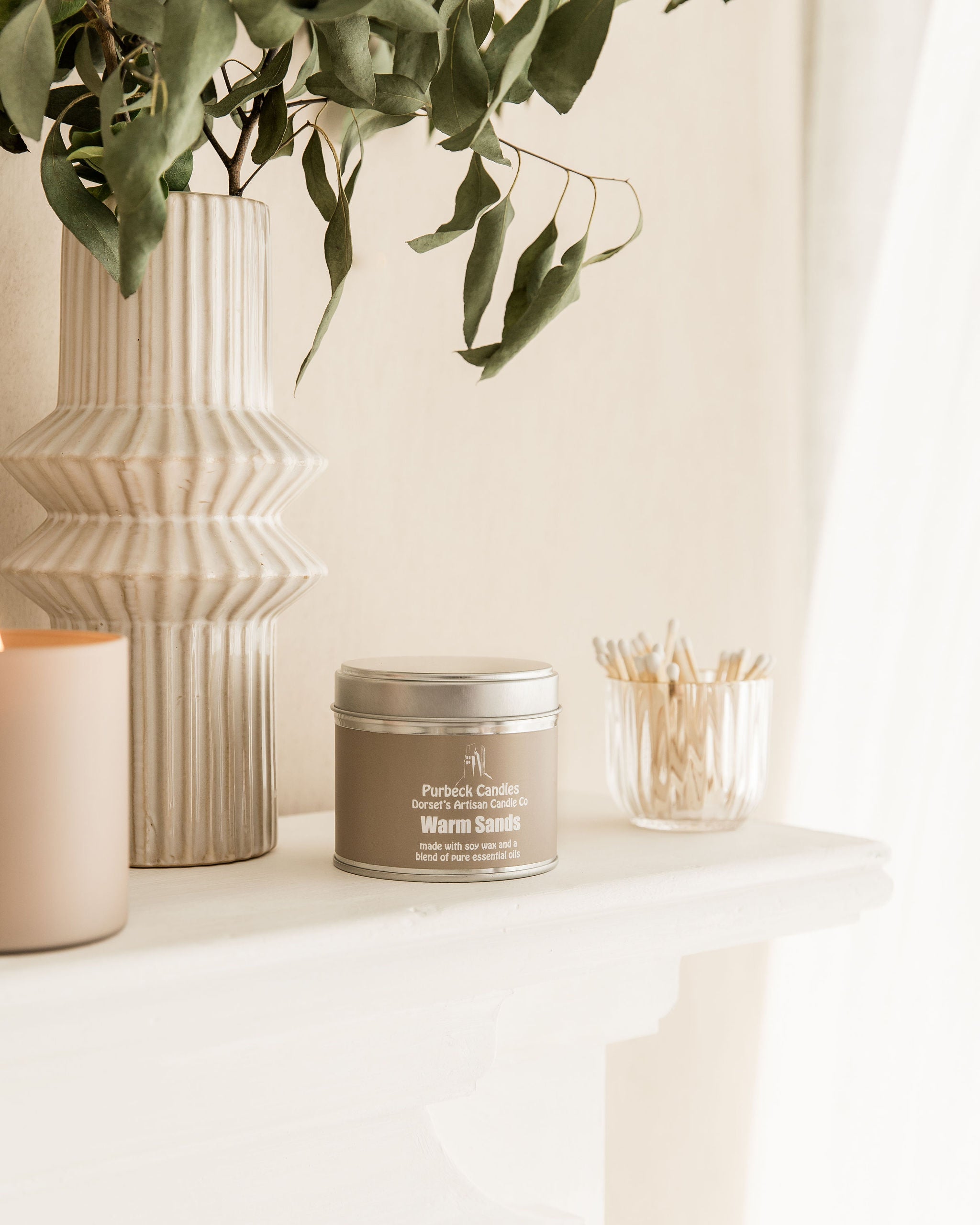 Candle with packaging on a table next to decorative items