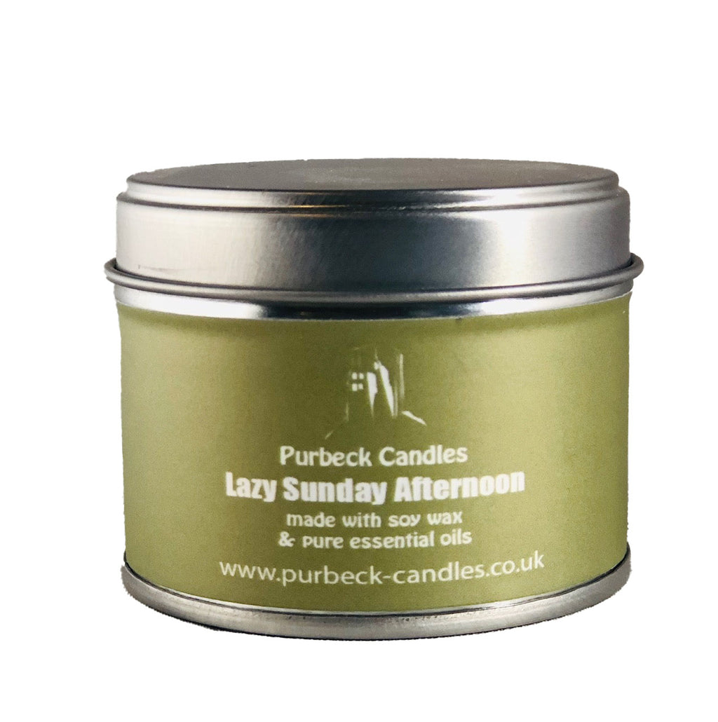 Green candle tin with silver lid labeled 'Purbeck Candles Lazy Sunday Afternoon' on a white background